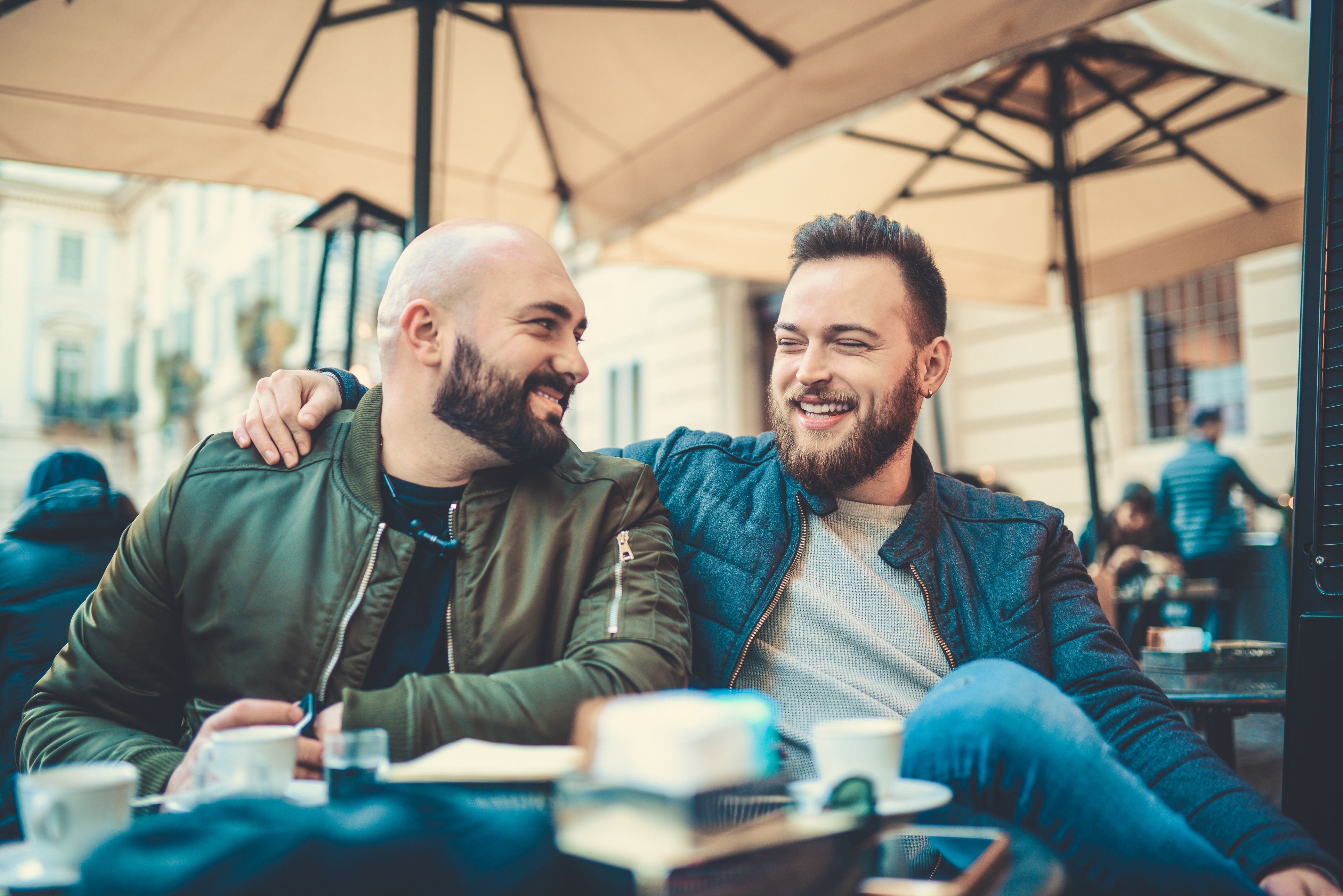 Two Smiling Friends Drinking Coffee and Talking in Coffee Shop